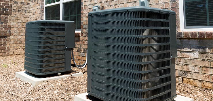 Two large outdoor air conditioning units on cement platforms.