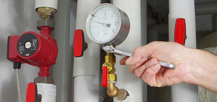 A furnace installation technician is installing a pressure gauge.