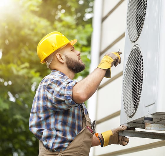 A technician is inspecting the fans of a residential HVAC system.